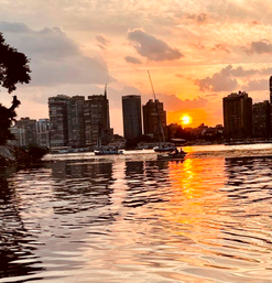Boote auf dem Nil vor Skyline im Abendrot mit Spiegelung im Wasser