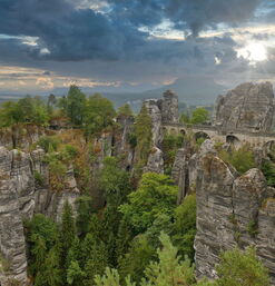 Steinbrücke zwischen markanten Felsen mit Blick auf bewaldete Landschaft