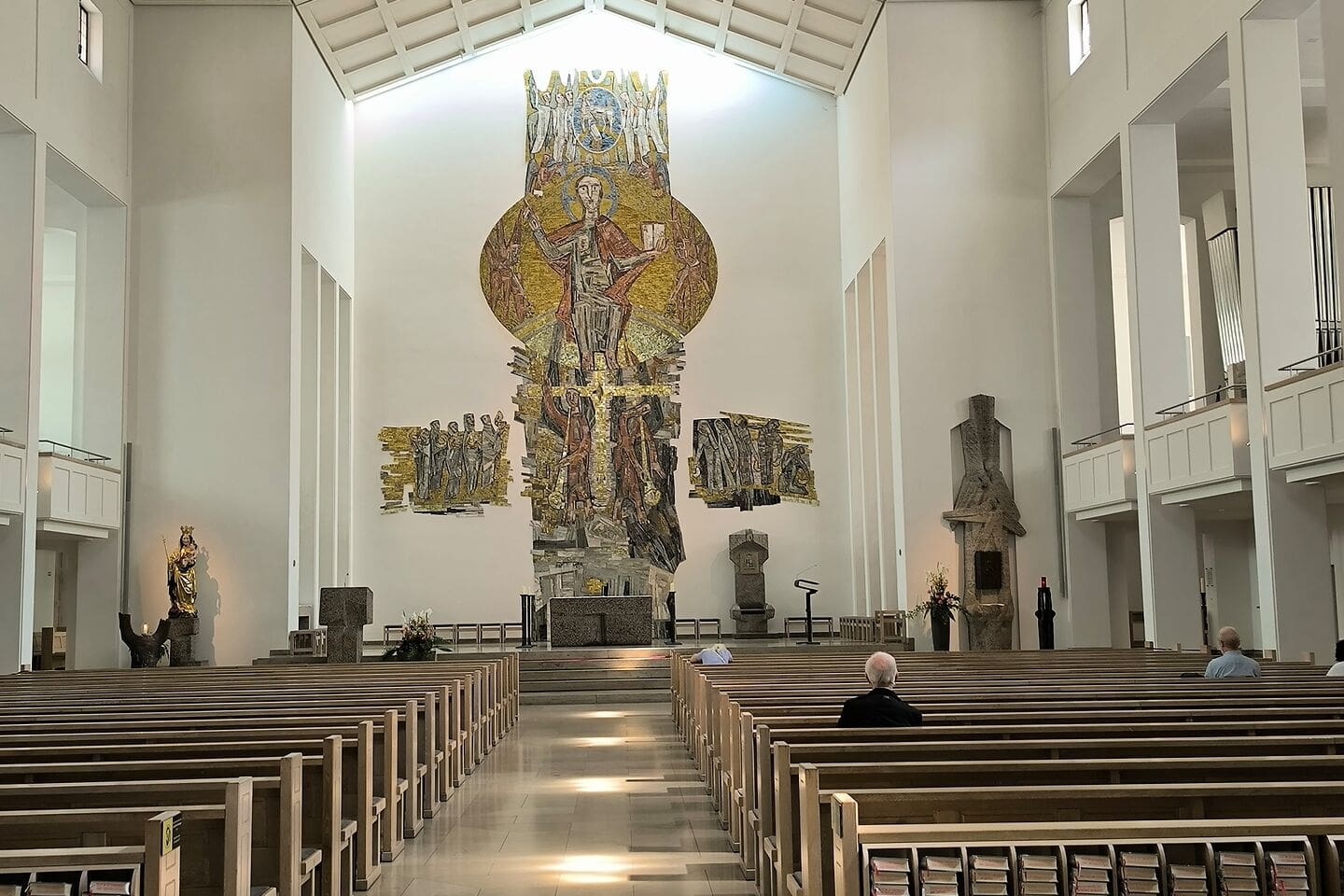 Kirchenschiff mit Bänken und großem goldfarbenem Mosaikaltar