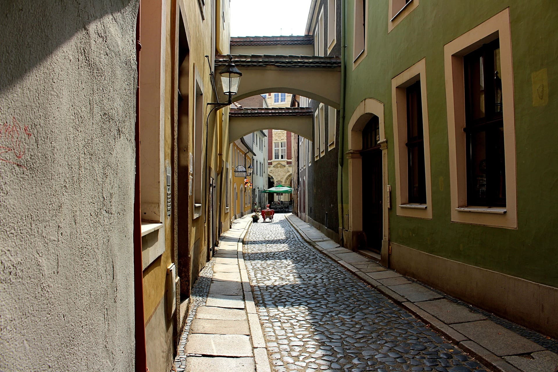 Schmale Kopfsteinpflastergasse mit Arkaden und bunten Fassaden
