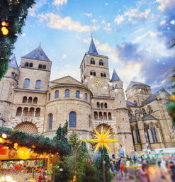 Festlich geschmückter Weihnachtsmarkt vor romanischem Dom