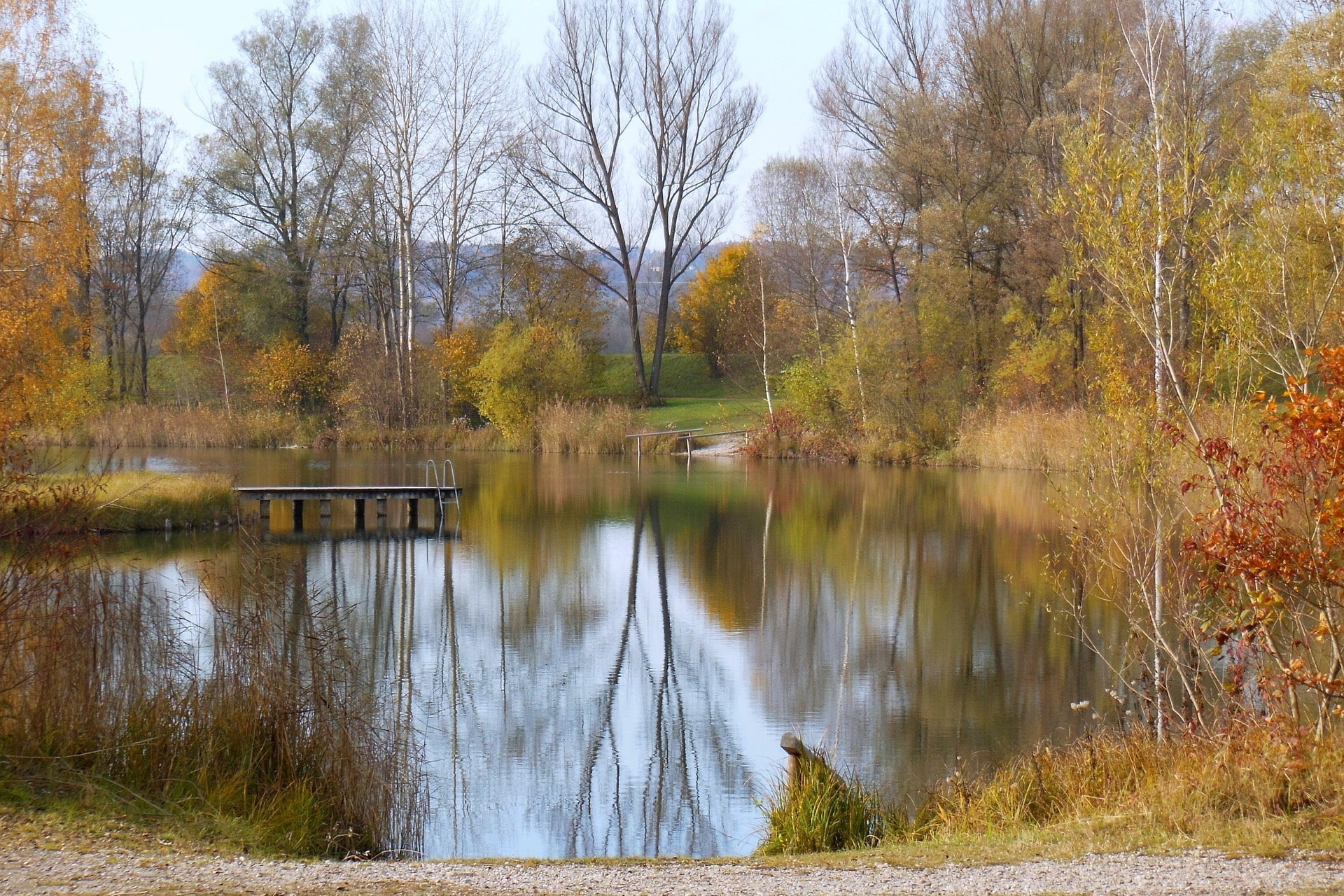 Kleiner See mit Steg und herbstlich bunten Bäumen