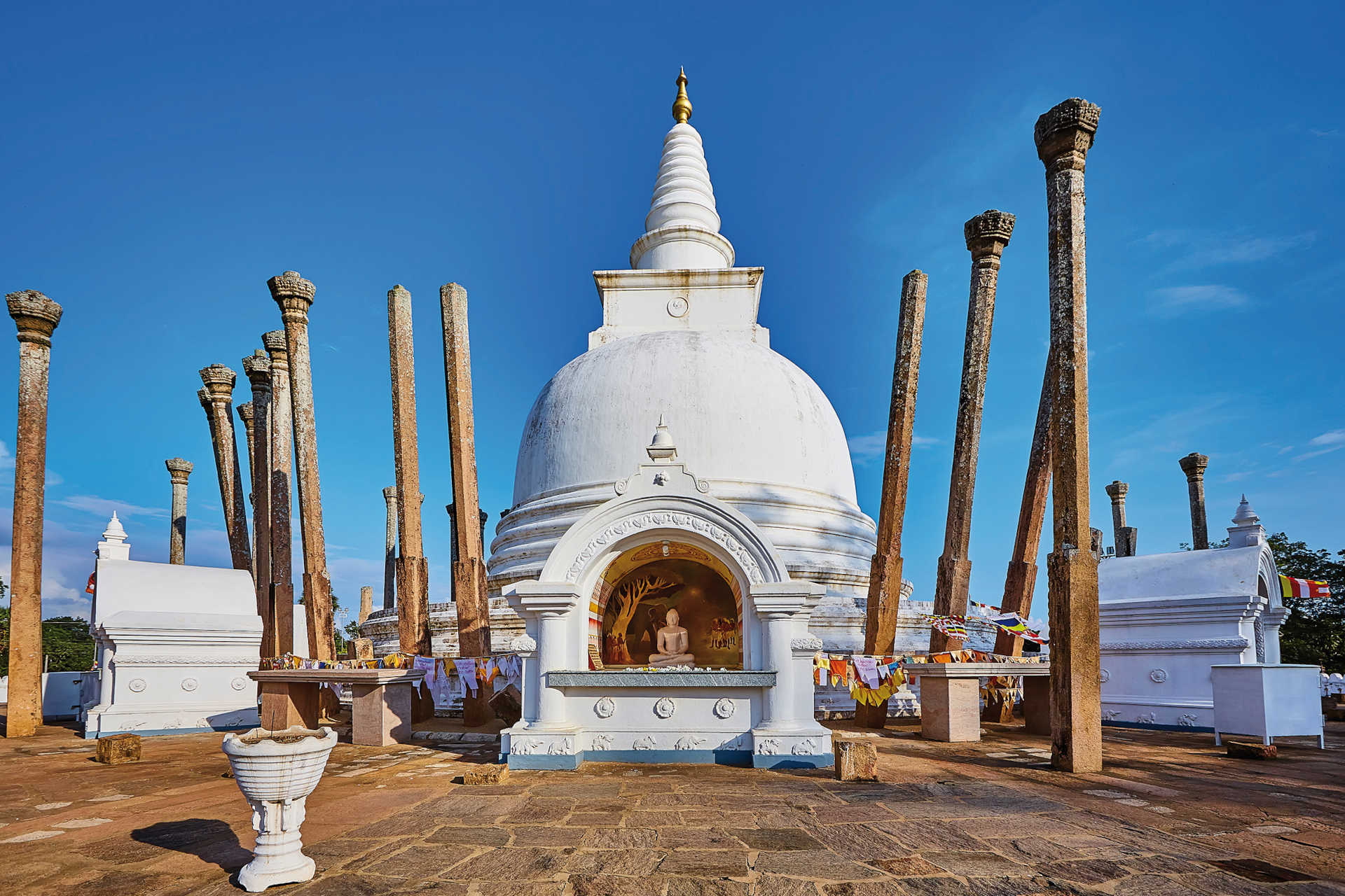 Weiße buddhistische Stupa mit Buddha-Nische und alten Steinsäulen in Anuradhapura, Sri Lanka