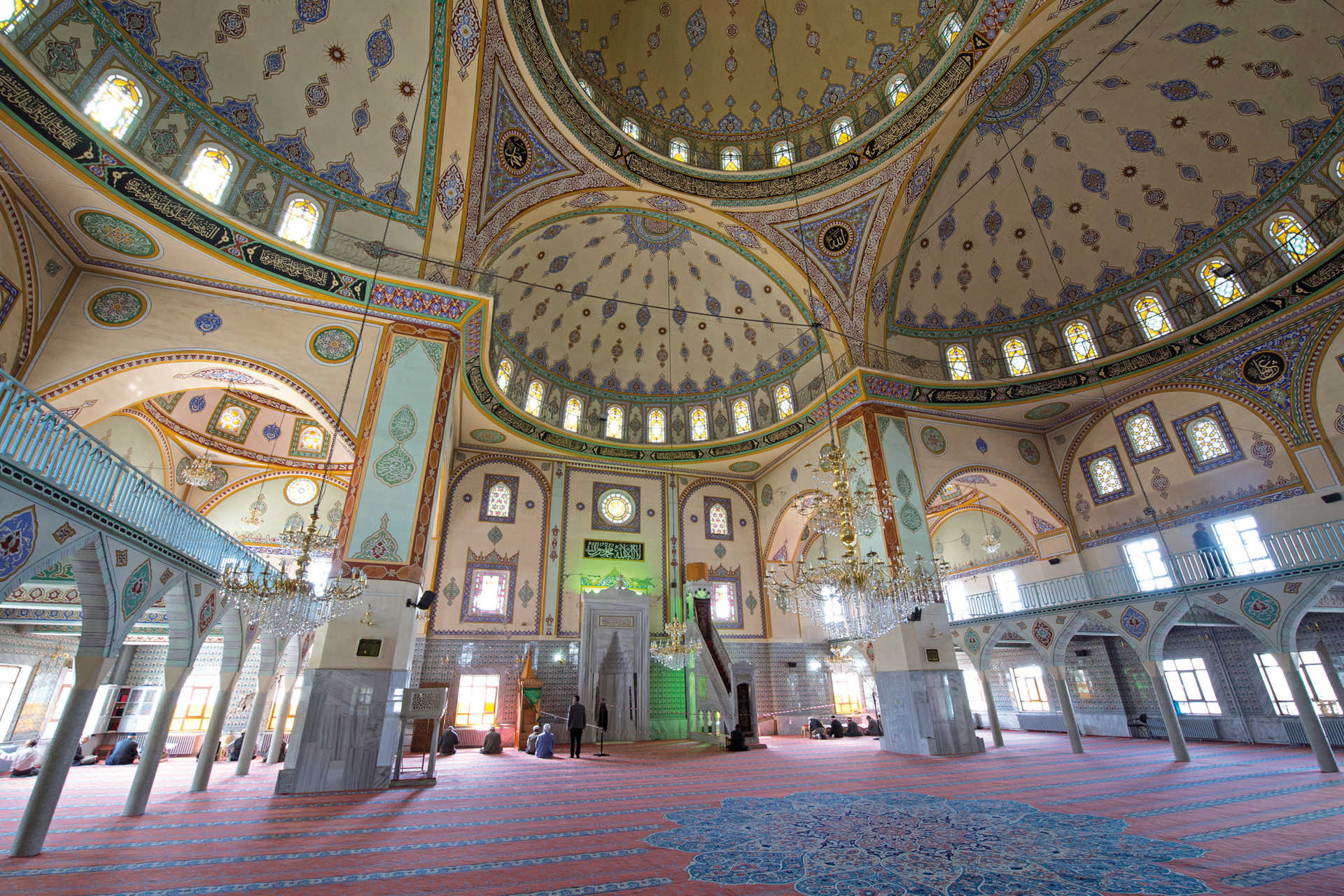 Prächtig verzierter Kuppelraum mit Kronleuchtern, Teppichen und arabischen Inschriften
