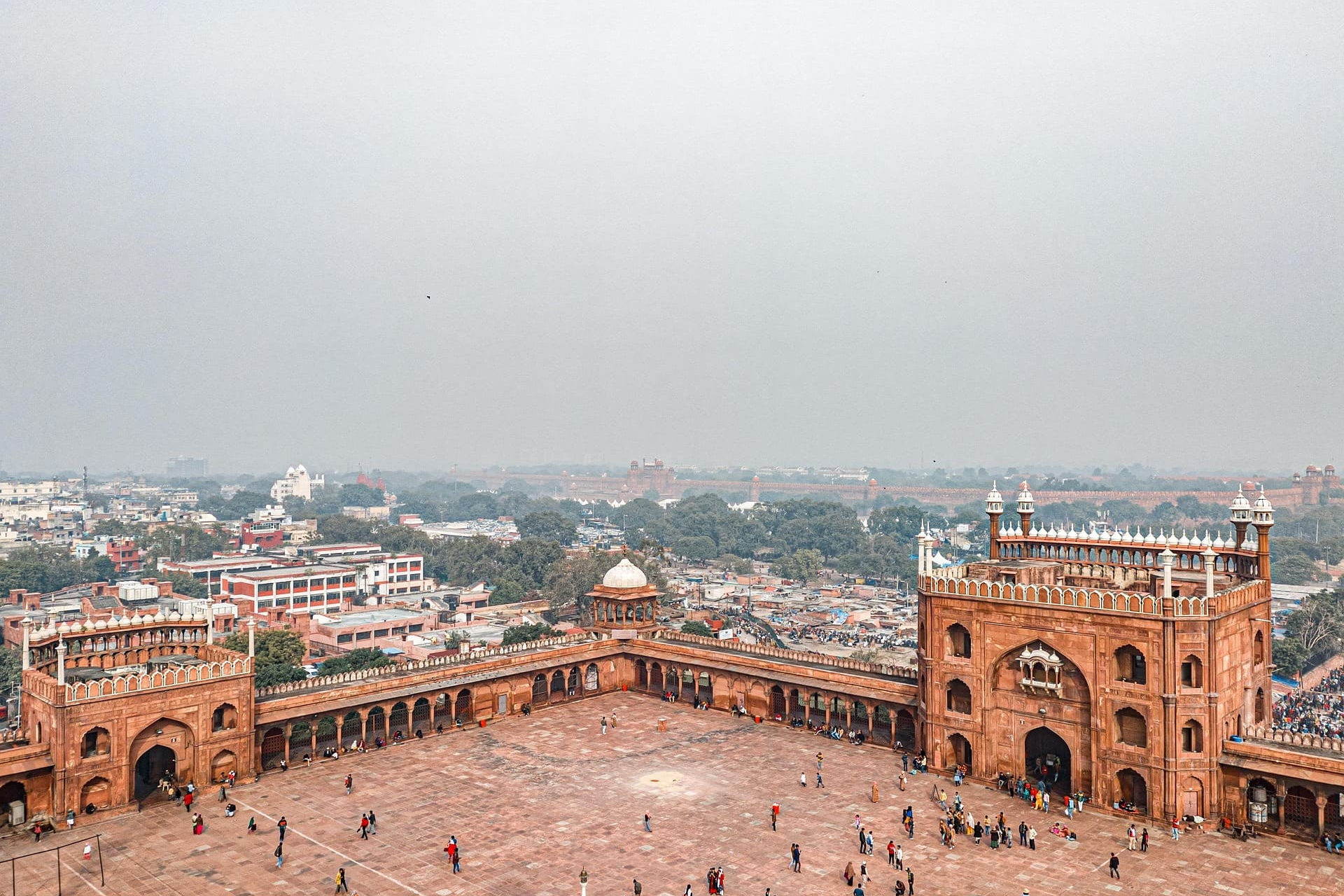 Großer Innenhof mit roten Torbauten und Menschen in Delhi