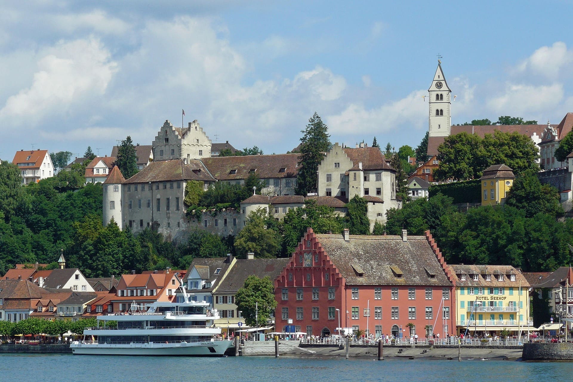 Bunte Häuser und Schloss über Hafen mit Ausflugsschiff am Bodensee