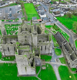 Mächtige Burgruine mit Friedhof auf grünem Hügel in Irland