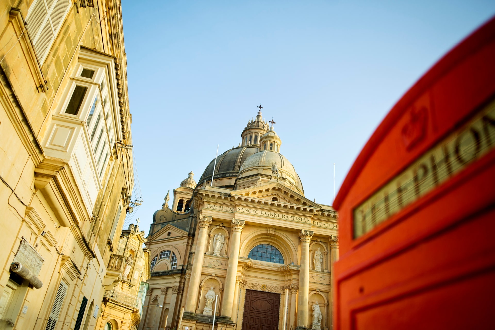Historische Kirche in Valletta mit britischer Telefonzelle im Vordergrund