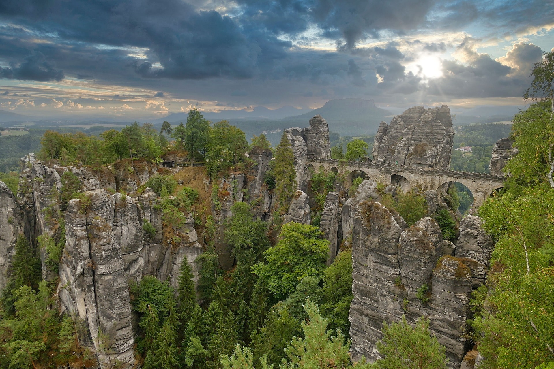Steinbrücke zwischen markanten Felsen mit Blick auf bewaldete Landschaft