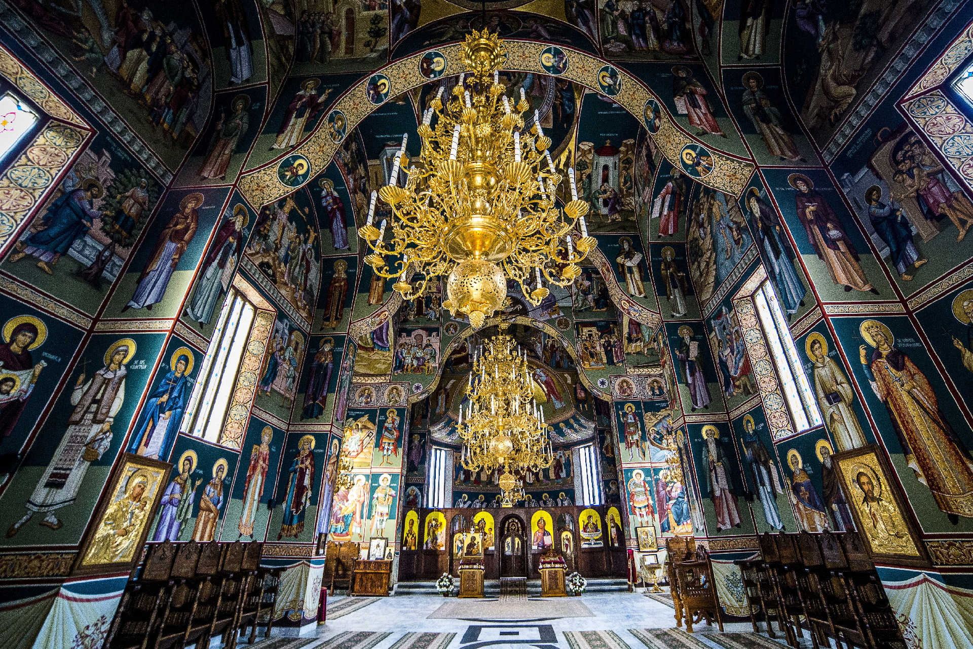 Innenraum mit goldenen Kronleuchtern und Wandmalereien in orthodoxer Kirche