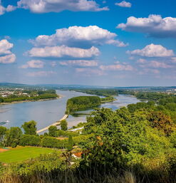 Breiter Fluss mit grünen Uferlandschaften und Wolkenhimmel