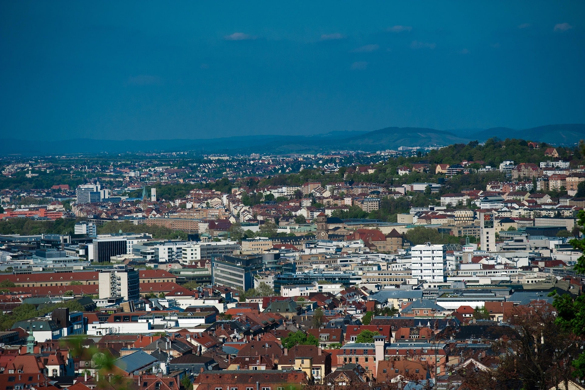 Blick über die Innenstadt von Stuttgart mit Hügeln im Hintergrund bei klarem Himmel