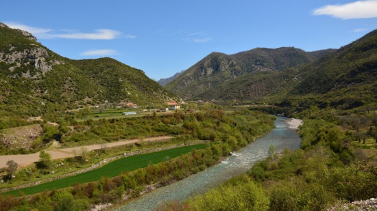 Klarer Fluss schlängelt sich durch grünes Tal zwischen Bergen
