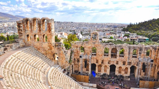 Steinernes Theater mit halbkreisförmigen Rängen vor Stadtpanorama