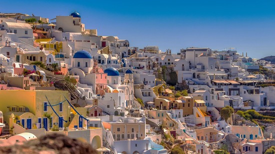 Dichte Häuser mit blauen Kuppeln leuchten unter klarem Himmel