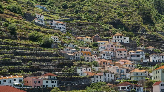 Bunte Häuser schmiegen sich an grüne Terrassenhänge des Berges