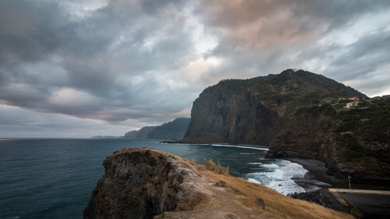 Dunkle Klippen ragen über das Meer unter dramatischem Wolkenhimmel