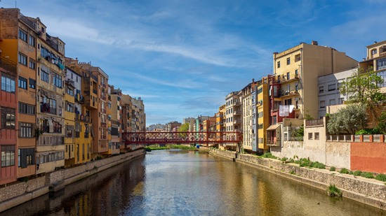 Reihen farbiger Fassaden spiegeln sich im Wasser unter blauem Himmel