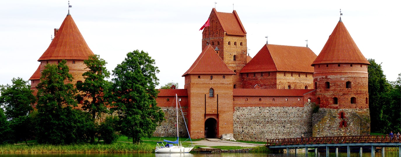 Backsteinburg auf Insel im See mit roten Dächern und Segelboot davor