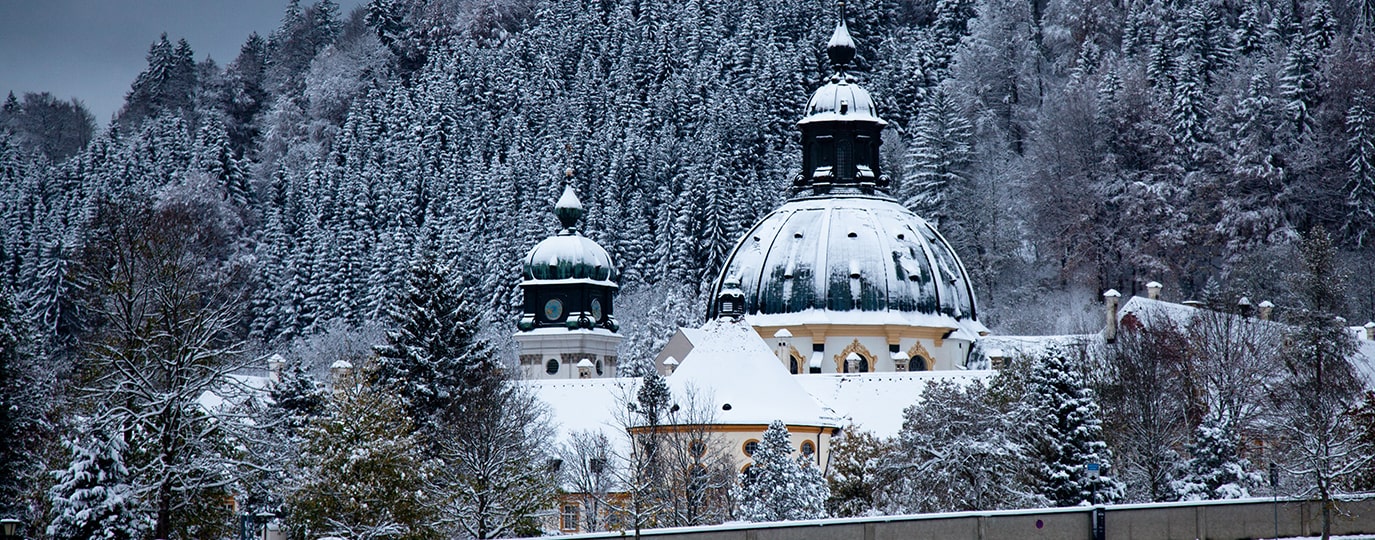 Verschneite Klosterkuppel vor dichtem Nadelwald