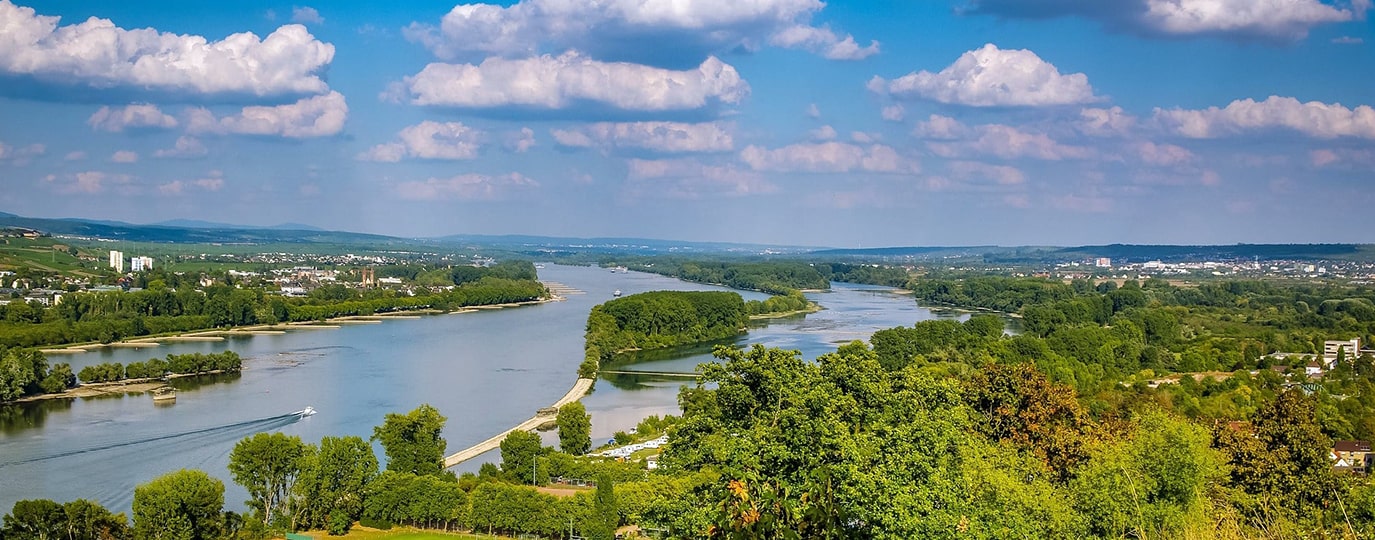 Breiter Fluss mit grünen Uferlandschaften und Wolkenhimmel